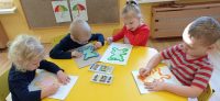 Dzieci obrysowują szablon misia pastelami