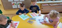 Dzieci rozcierają palcem pokolorowany pastelami kontur misia
