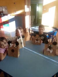 Dzieci siedzące przy stoliku z misiami wykonanymi z papierowej torebki i origamii z kół