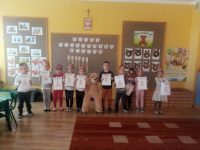 Dzieci stojące z dyplomami z okazji Dnia Pluszowego Misia